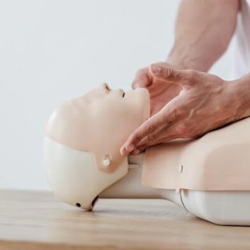 A person practicing CPR on a training mannequin, demonstrating chest compression techniques on a realistic, lifelike model.